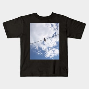 Girl in slingshot against blue cloudy sky Kids T-Shirt